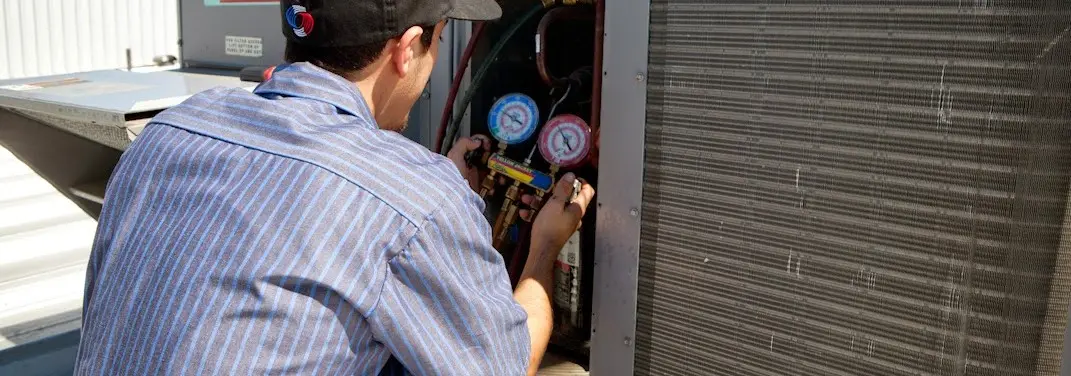HVAC technician servicing a condenser unit in East Bridgewater